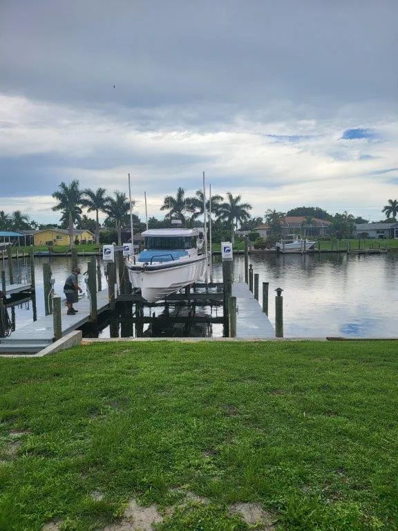Slide: The Image of 2024 Axopar 37 XC CROSS CABIN docked by a serene waterfront with palm trees. - 11