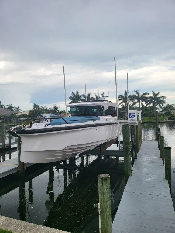 Slide: The Image of 2024 Axopar 37 XC CROSS CABIN docked by palm trees, overcast sky. - 5