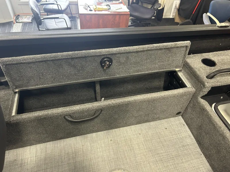 Slide: The Image of 2024 Alumacraft Competitor FSX 185 boat interior storage compartment, open with gray carpeting. - 11