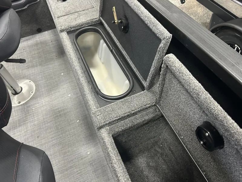 Slide: The Image of 2024 Alumacraft Competitor FSX 185 interior storage compartments with gray carpeting and seating. - 12