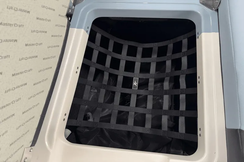Slide: The Image of 2025 MasterCraft XT22 storage compartment with black netting and branded interior. - 15