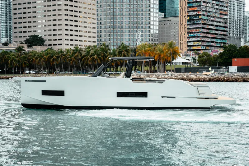 Slide: The Image of 2025 De Antonio Yachts D50 OPEN cruising near city skyline and palm trees. - 4