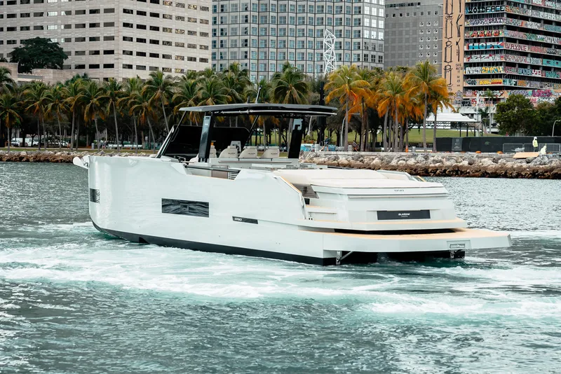Slide: The Image of 2025 De Antonio Yachts D50 OPEN cruising near a city waterfront with palm trees. - 5