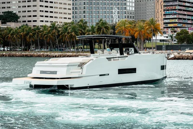 Slide: The Image of 2025 De Antonio Yachts D50 OPEN cruising near a city waterfront. - 7