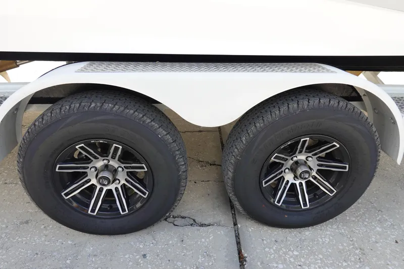 Slide: The Image of Trailer wheels of 2025 Malibu 23 LSV WAKESETTER boat on concrete surface. - 36