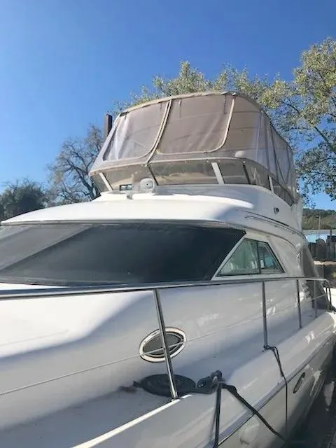 Slide: The Image of 2000 Sea Ray 400 Sedan Bridge yacht with flybridge, docked under clear blue sky. - 2