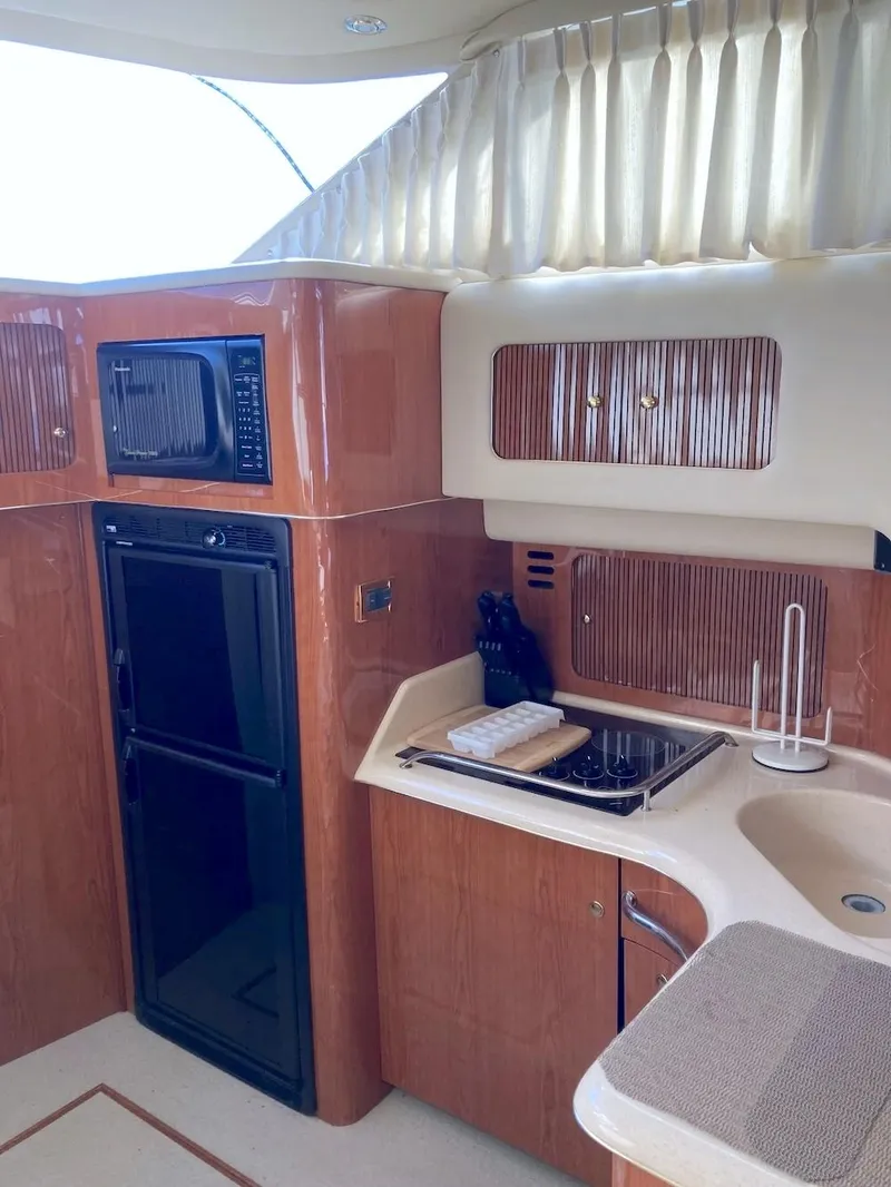Slide: The Image of Interior of 2000 Sea Ray 400 Sedan Bridge yacht kitchen with wood cabinetry and appliances. - 7