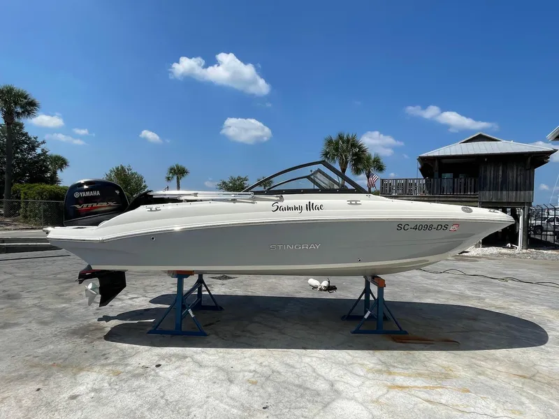 Slide: The Image of 2021 Stingray 191 DC boat on stands, sunny day, palm trees in background. - 2