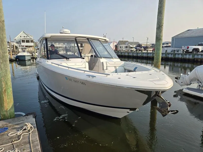 Slide: The Image of 2022 Regal LX36 boat docked in a marina, featuring sleek white design. - 2
