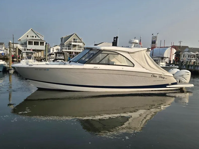 Slide: The Image of 2022 Regal LX36 boat docked in a marina, reflecting on calm water. - 4