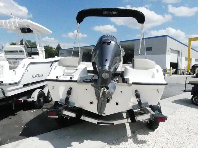 Slide: The Image of 2025 Key West 203 FS boat with outboard motor, parked outdoors under blue sky. - 5