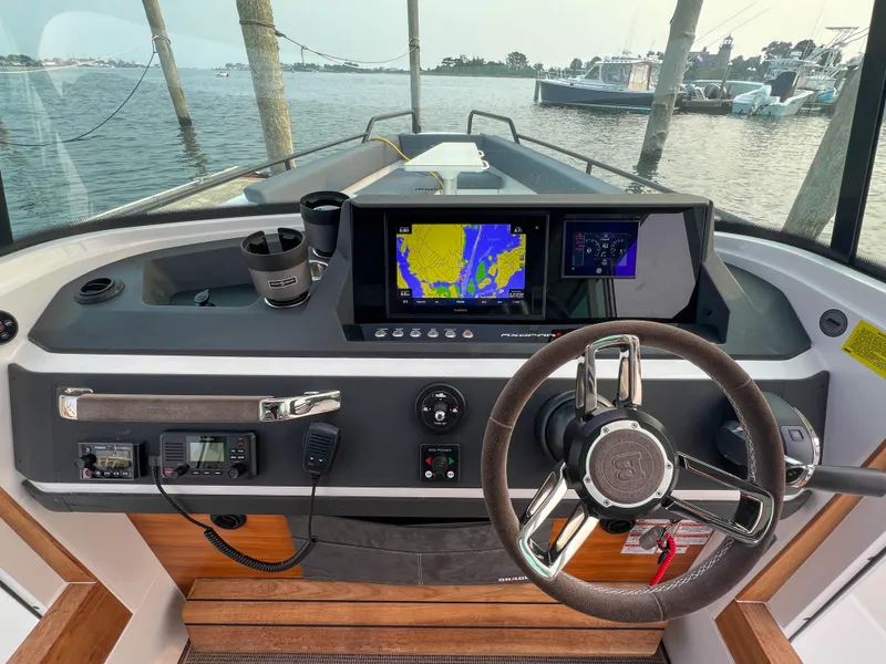 Slide: The Image of 2020 Axopar 28 CABIN boat dashboard with navigation screens and steering wheel. - 13