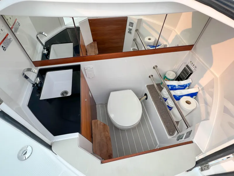 Slide: The Image of 2020 Axopar 28 CABIN bathroom with sink, toilet, and storage shelves. - 24