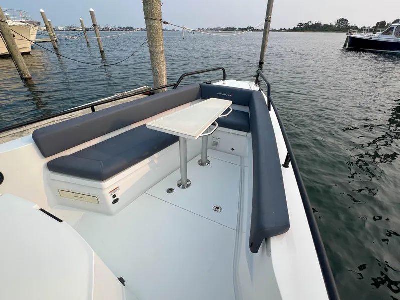 Slide: The Image of 2020 Axopar 28 CABIN boat with seating area and table on calm water. - 6