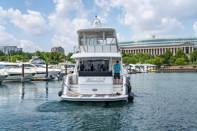Slide: The Image of Neptunus 62 Flybridge yacht, 2005 model, docked in a marina with cityscape background. - 6