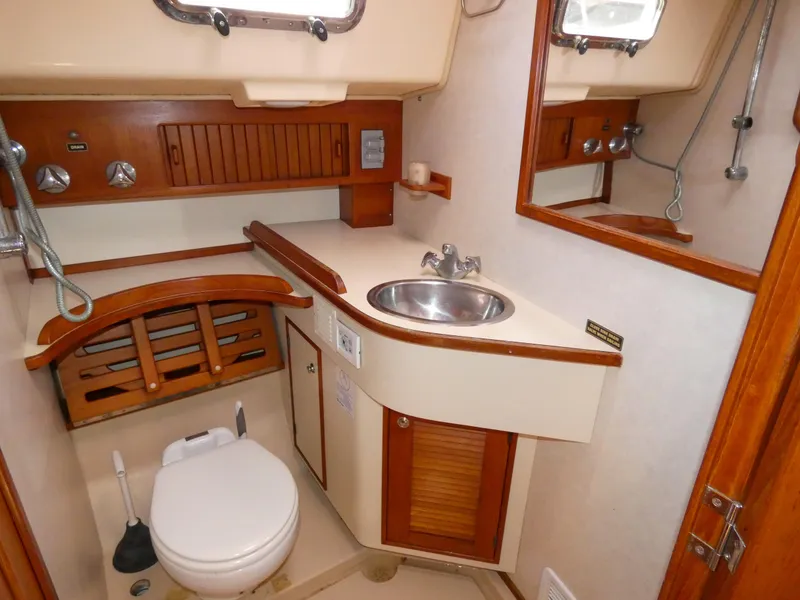 Slide: The Image of Island Packet 420 yacht interior, bathroom with wood accents, sink, and toilet. - 19
