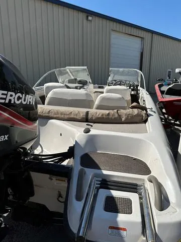 Slide: The Image of 2005 Sun Tracker 189 SPORT boat with Mercury outboard motor, parked near a warehouse. - 3