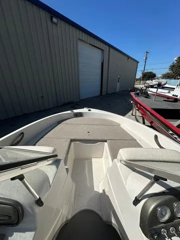 Slide: The Image of 2005 Sun Tracker 189 SPORT boat interior, parked near a warehouse under clear blue sky. - 6