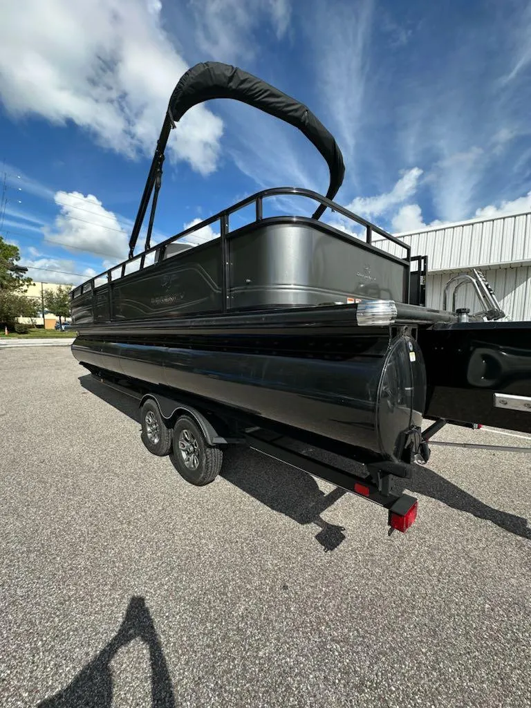 Slide: The Image of 2024 Regency 250 DL3 pontoon boat on trailer under blue sky. - 2