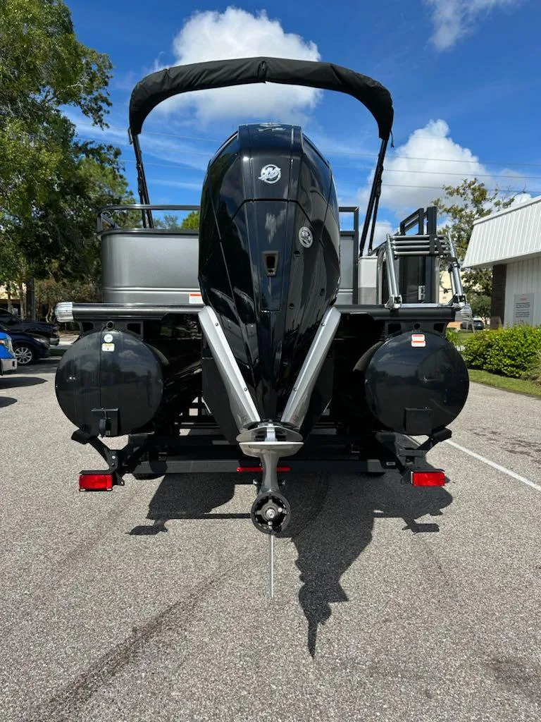 Slide: The Image of 2024 Regency 250 DL3 pontoon boat with powerful outboard motor, parked on a sunny day. - 3