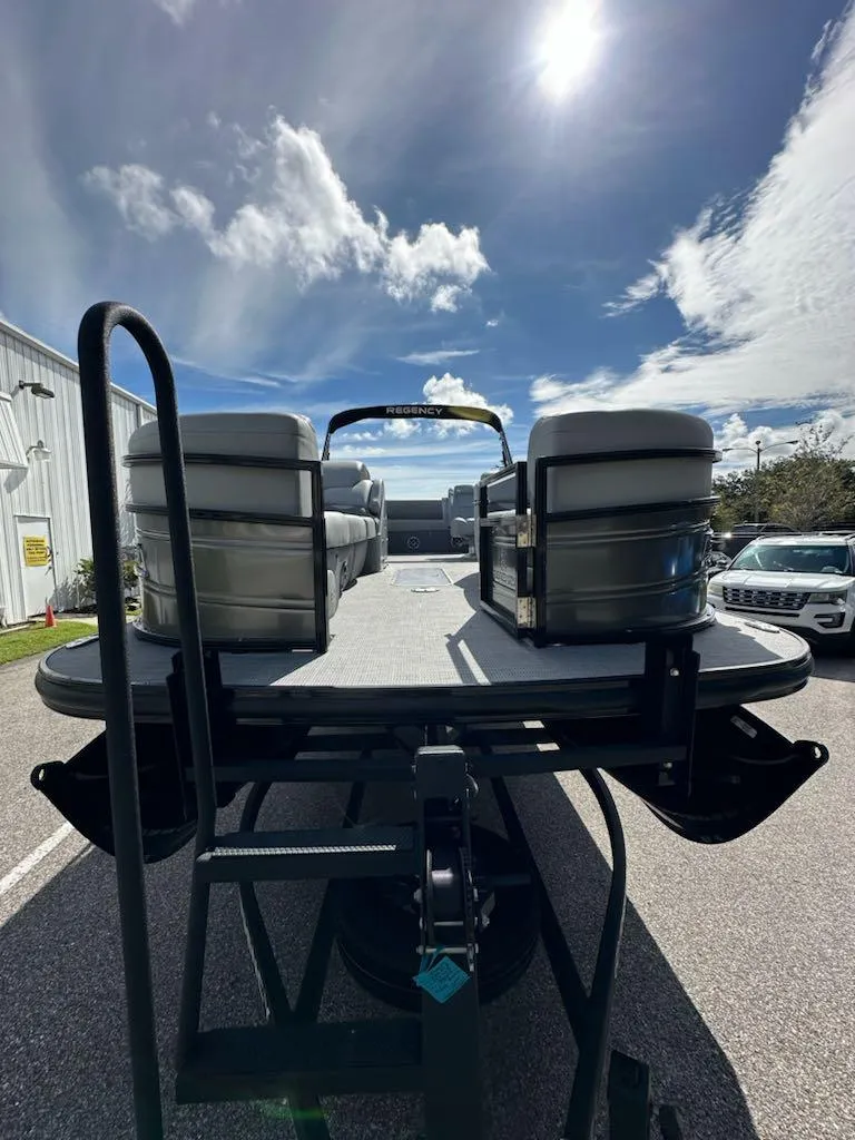 Slide: The Image of 2024 Regency 250 DL3 pontoon boat on trailer under sunny sky. - 4