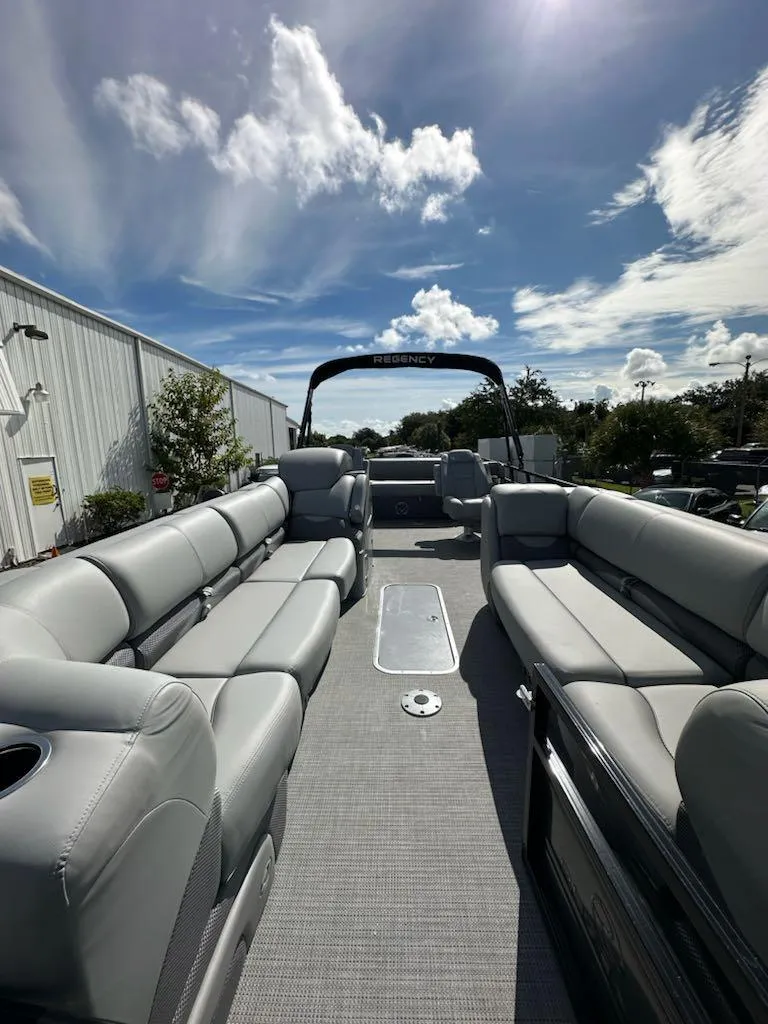 Slide: The Image of 2024 Regency 250 DL3 pontoon boat with spacious seating under a bright blue sky. - 7