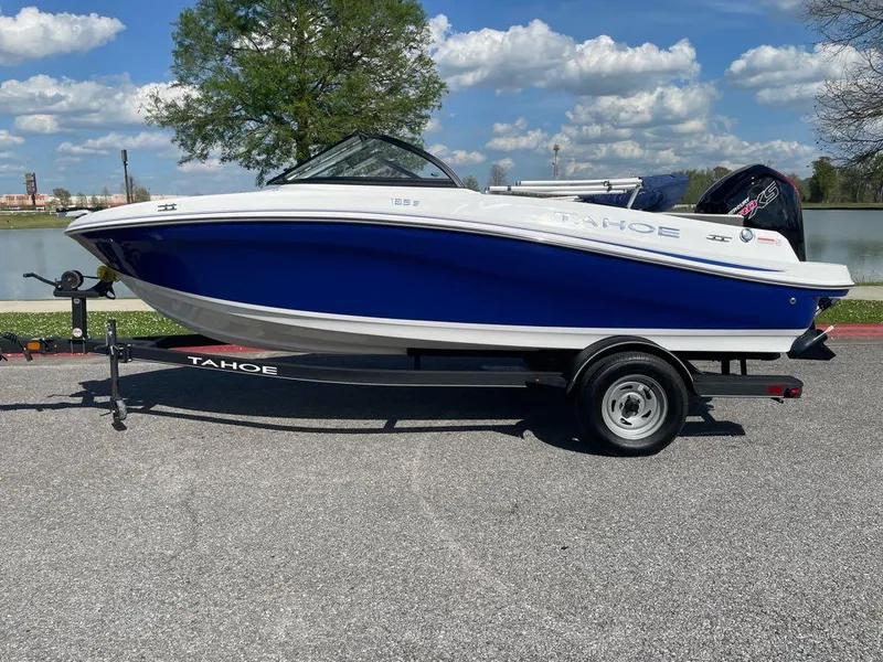 The Image of 2024 Tahoe 185 S boat on trailer, blue and white design, parked outdoors. - 0