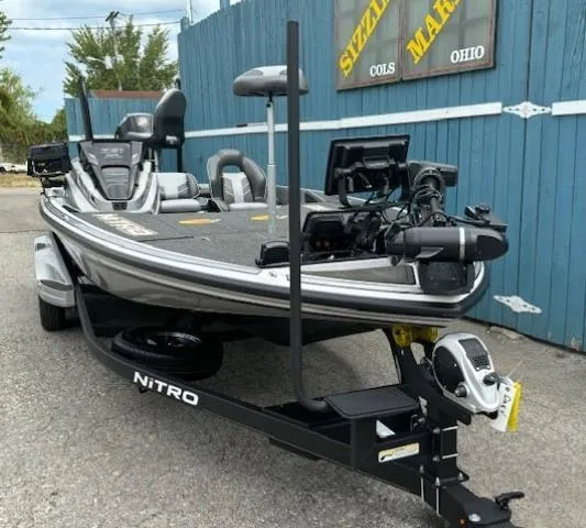 Slide: The Image of 2023 Nitro Z21 XL fishing boat on trailer, parked near blue fence. - 2