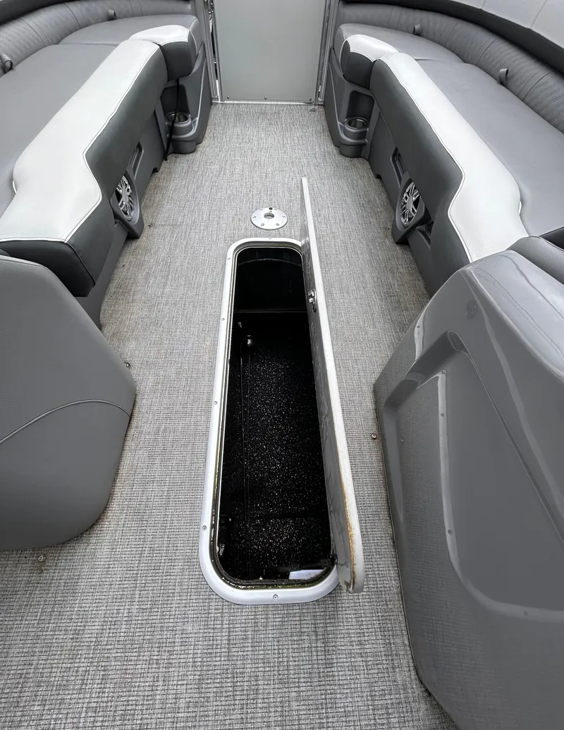 Slide: The Image of 2021 Avalon Catalina Cruise 25 interior with open storage compartment, gray seating, and carpeted floor. - 17