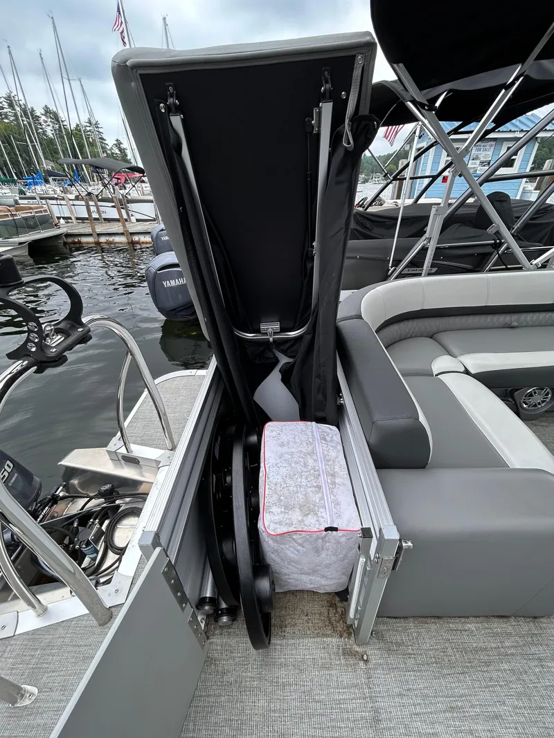 Slide: The Image of 2021 Avalon Catalina Cruise 25 boat storage compartment with seating and marina background. - 36