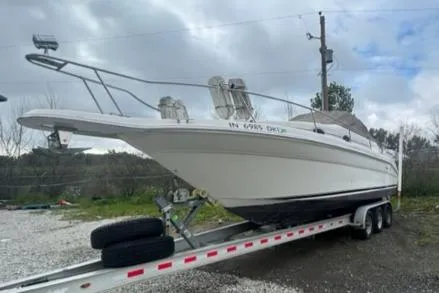 Slide: The Image of 1997 Sea Ray 270 Sundancer on trailer, parked outdoors under cloudy sky. - 6