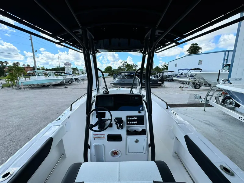 Slide: The Image of Edgewater 208 CC 2025 boat interior with steering wheel and controls, parked outdoors. - 10