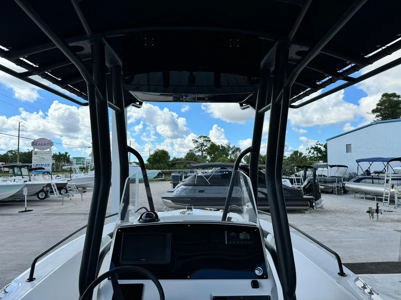 Slide: The Image of 2025 Edgewater 208 CC boat interior with console, parked at a marina under a blue sky. - 11