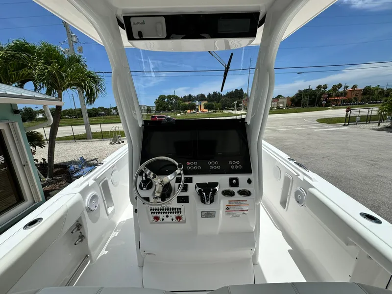 Slide: The Image of 2025 Edgewater 262 CC boat console with steering wheel and controls, parked outdoors. - 14