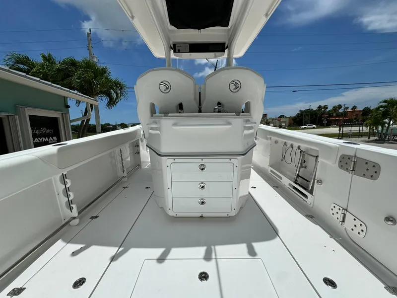 Slide: The Image of 2025 Edgewater 262 CC boat interior with dual seats and storage, under a clear blue sky. - 8