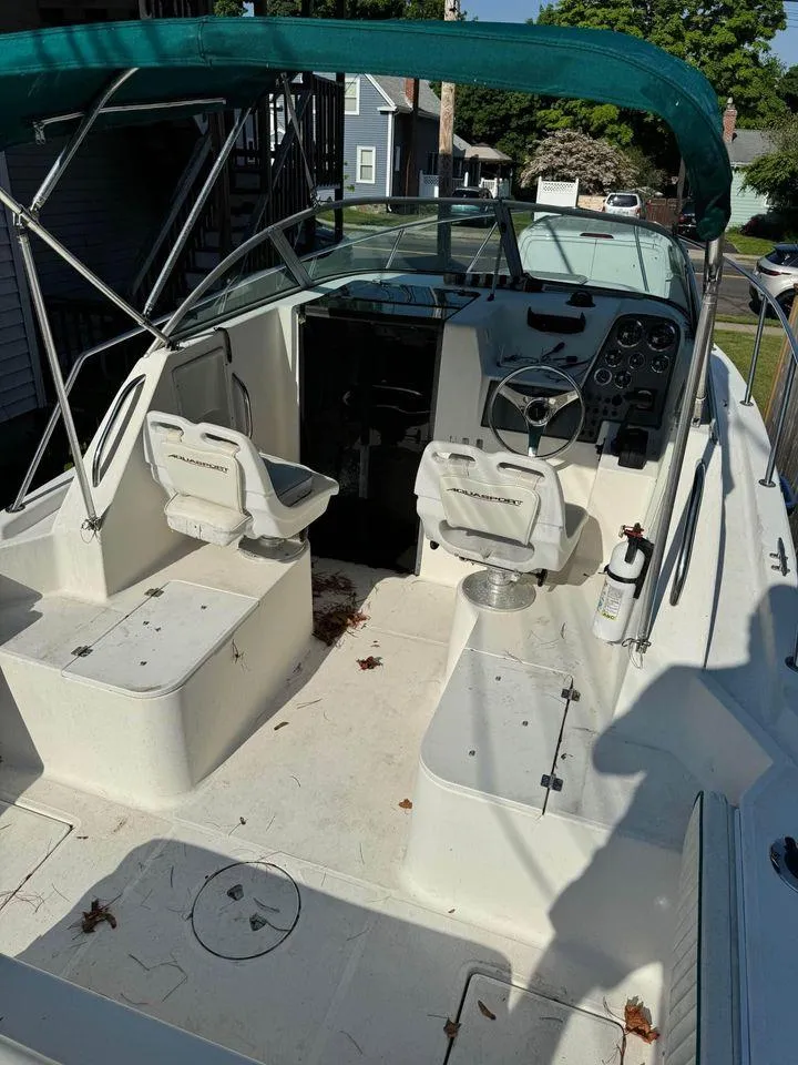 Slide: The Image of 2001 Aquasport 215 Explorer boat interior with seating and steering wheel, under a green canopy. - 3