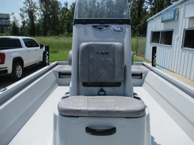 Slide: The Image of 2025 Avid 23 Mag boat interior with seating and console, parked outdoors. - 19