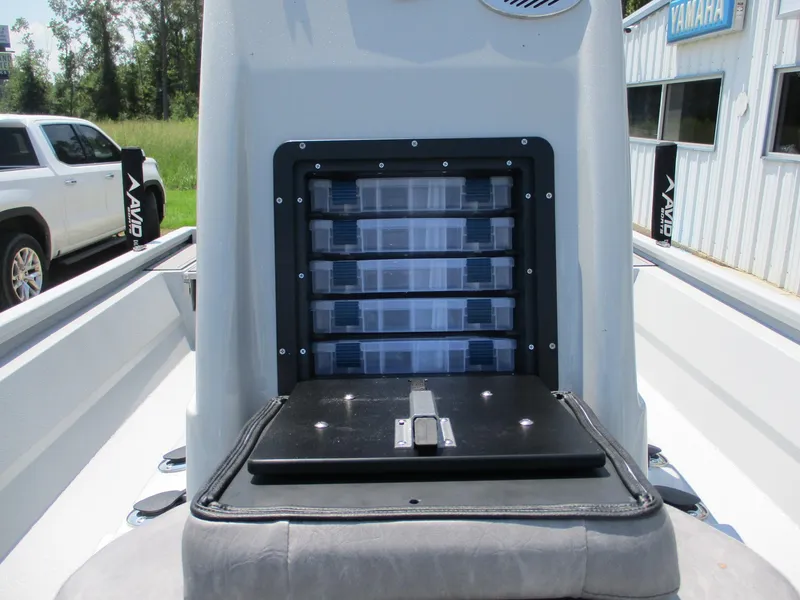 Slide: The Image of Avid 23 Mag 2025 boat storage compartment with tackle boxes, parked near a building. - 21
