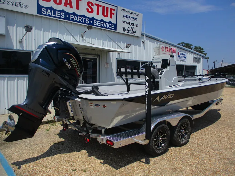 Slide: The Image of Avid 23 Mag 2025 boat on trailer outside dealership, featuring powerful outboard motor. - 6