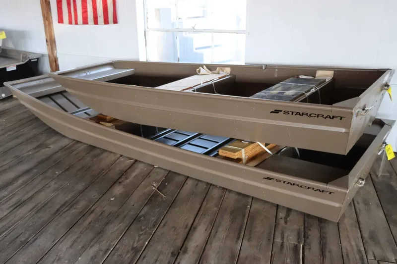 Slide: The Image of 2025 Starcraft 1436 JON TS boats stacked on wooden floor in showroom. - 3