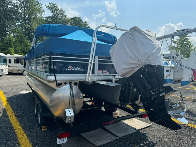 Slide: The Image of 2020 Tracker FISHIN 22 BARGE DLX pontoon boat on trailer, covered motor, sunny day. - 11