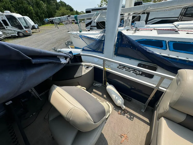 Slide: The Image of 2020 Tracker FISHIN 22 BARGE DLX interior with seating, docked near other boats. - 5