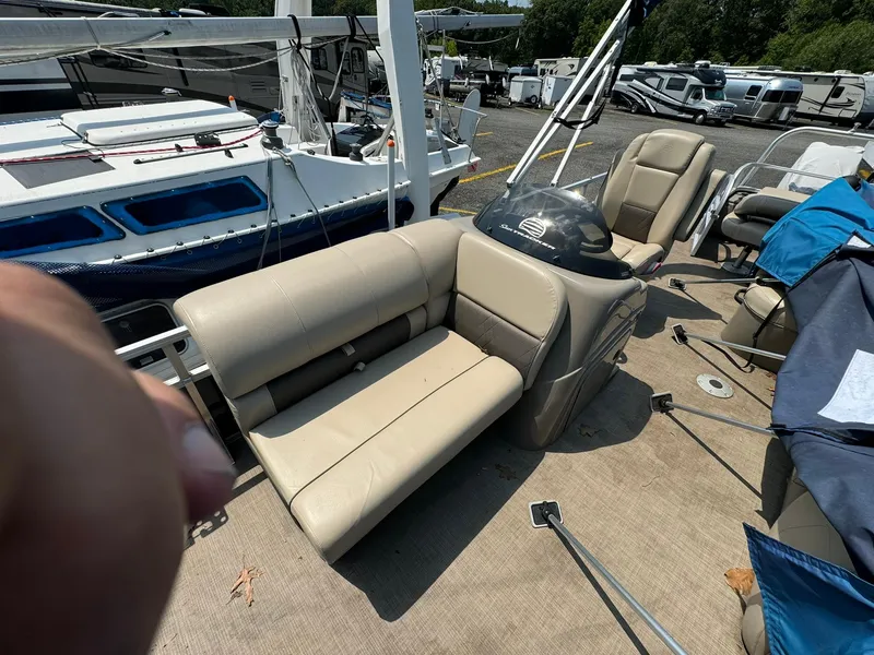 Slide: The Image of 2020 Tracker FISHIN 22 BARGE DLX pontoon boat with beige seating, docked near other boats. - 6