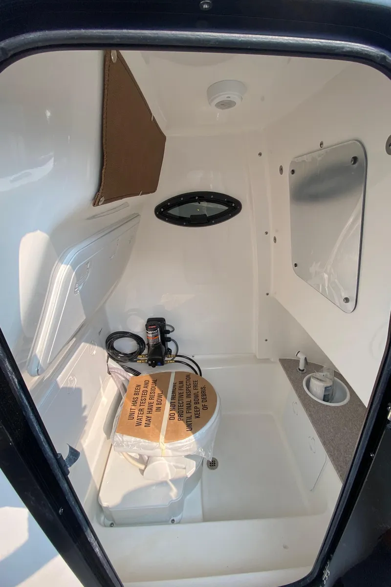 Slide: The Image of 2024 Sea Pro 242 Center Console interior cabin with compact amenities. - 18