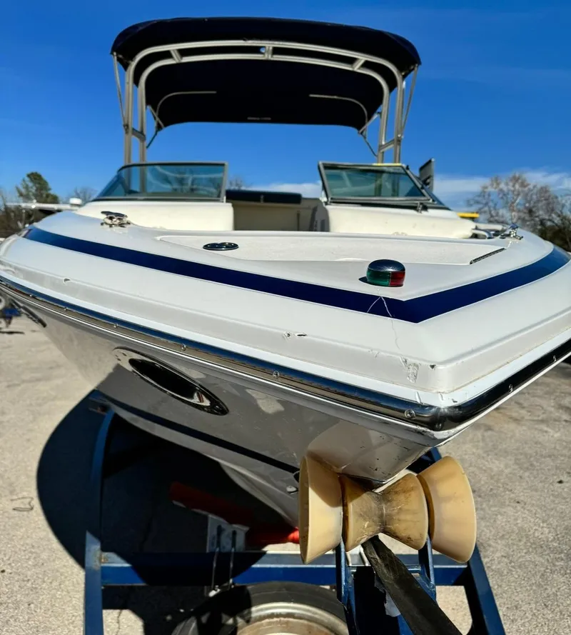 Slide: The Image of 2005 Cobalt GS242 boat with canopy, docked on trailer under clear blue sky. - 2