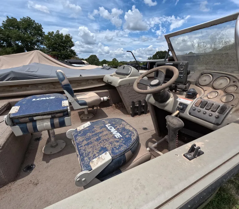 Slide: The Image of 2005 Lowe Fish & Ski FS175 boat interior with steering wheel and seats under a cloudy sky. - 13