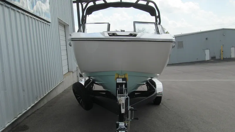 Slide: The Image of 2025 Yamaha Boats 222S on trailer, parked near industrial building. - 4