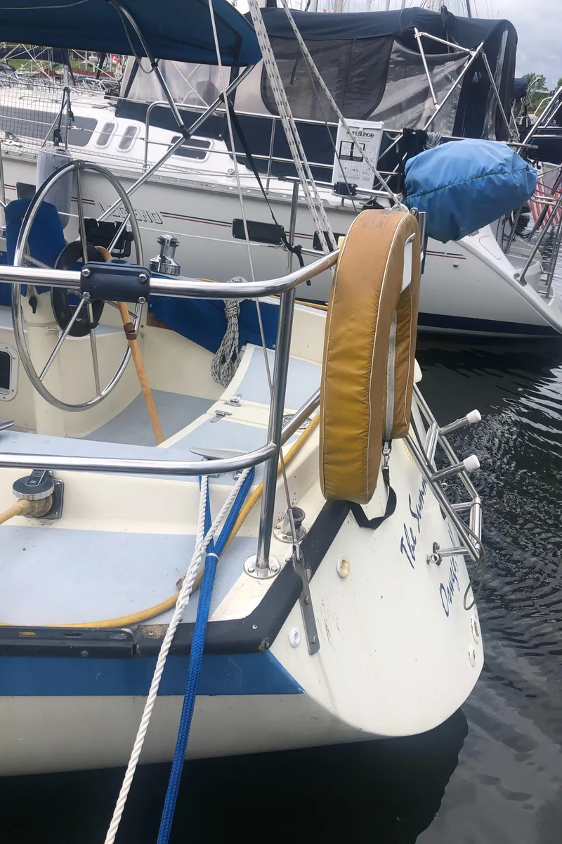 Slide: The Image of 1980 Lancer 36 sailboat docked, featuring a steering wheel and life preserver. - 10