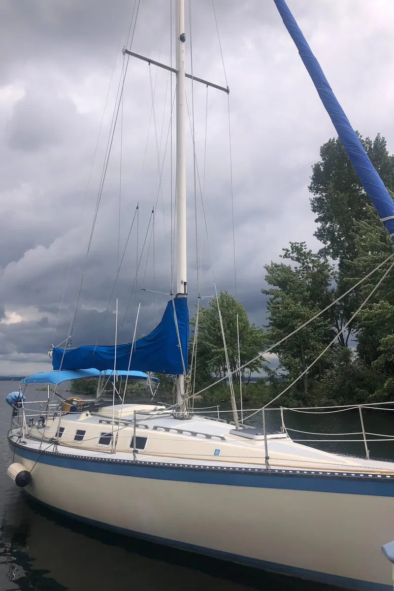 Slide: The Image of 1980 Lancer 36 sailboat with blue sail cover, docked under cloudy skies. - 2