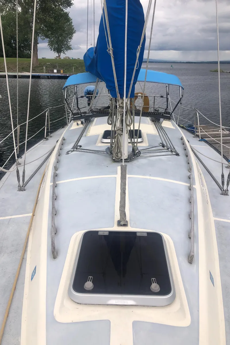 Slide: The Image of 1980 Lancer 36 sailboat with blue sail cover, docked on a calm lake. - 4